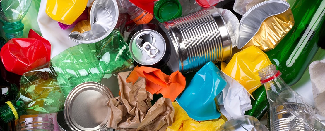 Ein Haufen gemischter Müll aus Plastikflaschen, Getränkedosen, Aluminiumverpackungen, Papier und Glasflaschen, symbolisiert Recycling, Mülltrennung und Müllvermeidung.