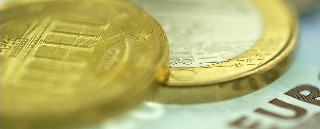 Makroaufnahme von Euro-Münzen und einem Geldschein mit Fokus auf Details und Prägung. Symbolbild für Bargeld abschaffen