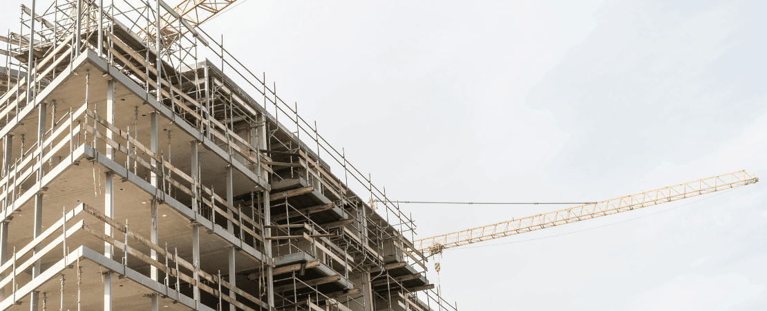 Mehrstöckiger Neubau im Rohbau mit Gerüsten und Baukran.