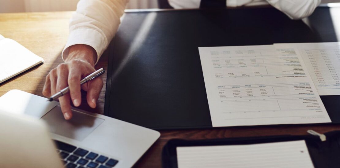 Tavolo da lavoro di un imprenditore che scrive e legge al pc lavorando