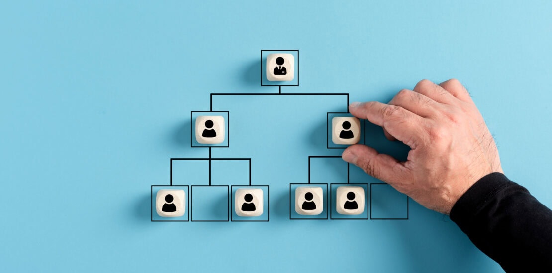 Concetto di organizzazione aziendale rappresentato con cubi di legno disposti a organigramma su sfondo blu