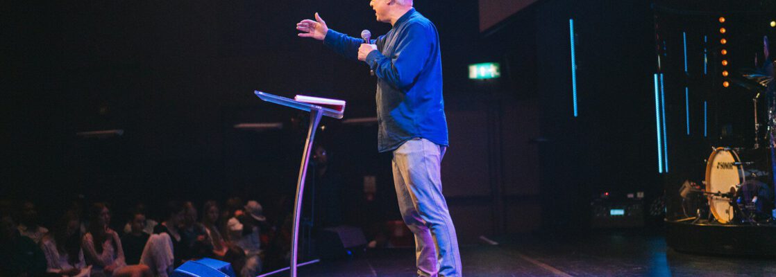 A man standing on top of a stage next to a microphone