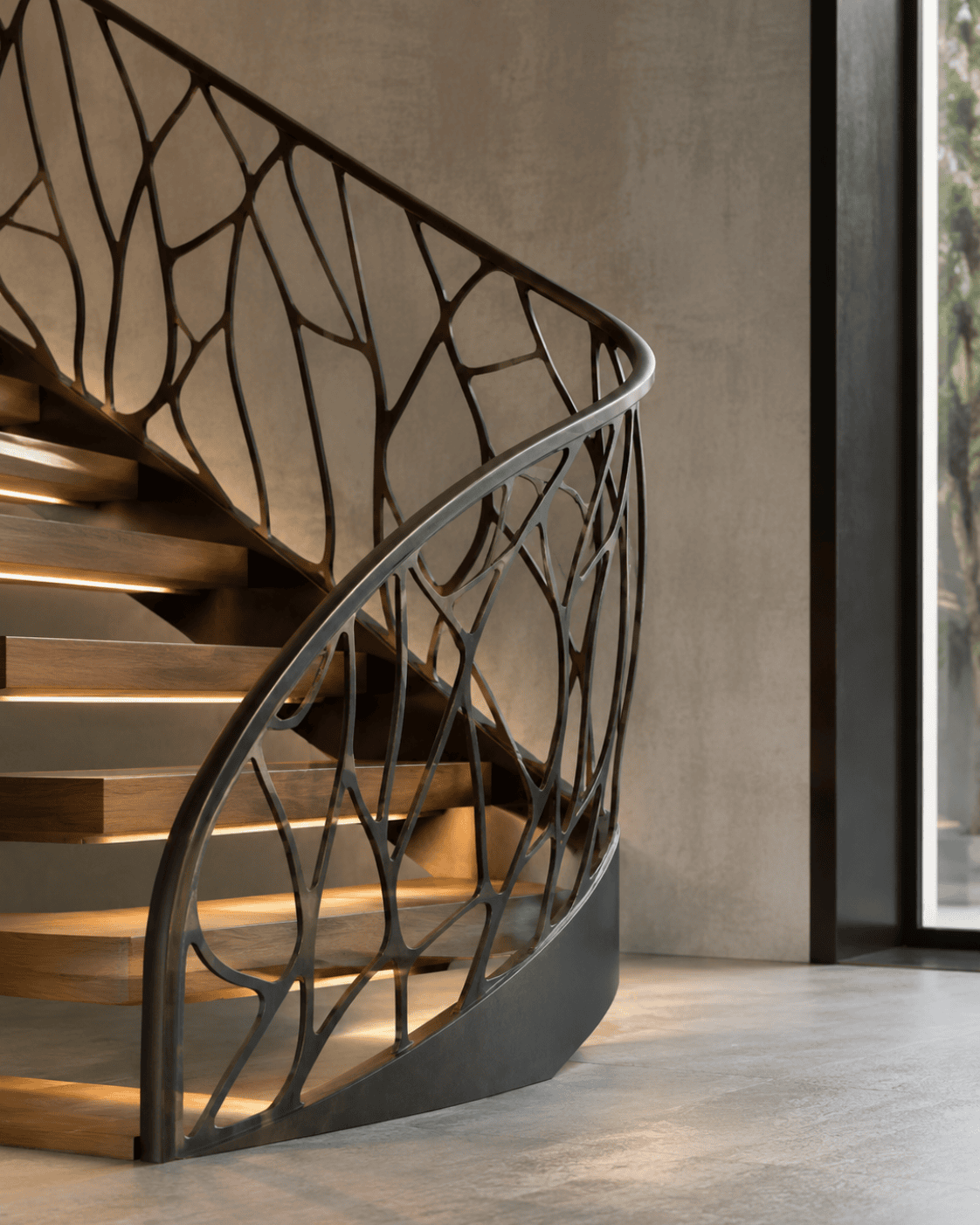 Stahl- und Metallbau Drost: Moderne, geschwungene Treppe aus Holz mit integrierter Stufenbeleuchtung und kunstvollem Metallgeländer im organischen Astmuster.