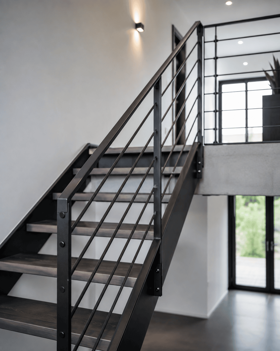 Moderne Innentreppe von Stahl- und Metallbau Drost mit dunklen Holzstufen und schwarzem Metallgeländer mit horizontalen Streben in einem zeitgenössischen Interieur.