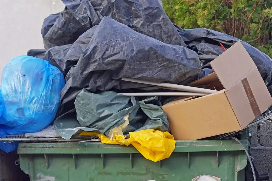 An image of overflowing recycling bin with various dicarded items