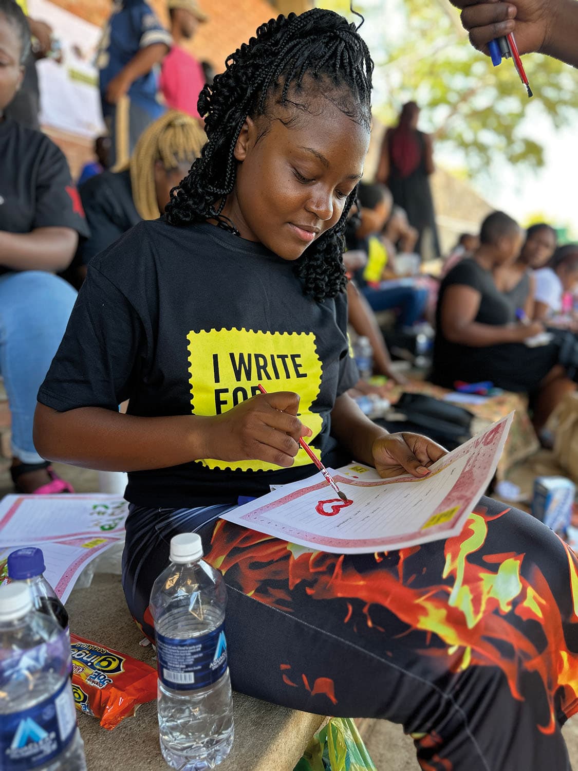 Girl drawing a heart on her letter at a. Write for Rights event