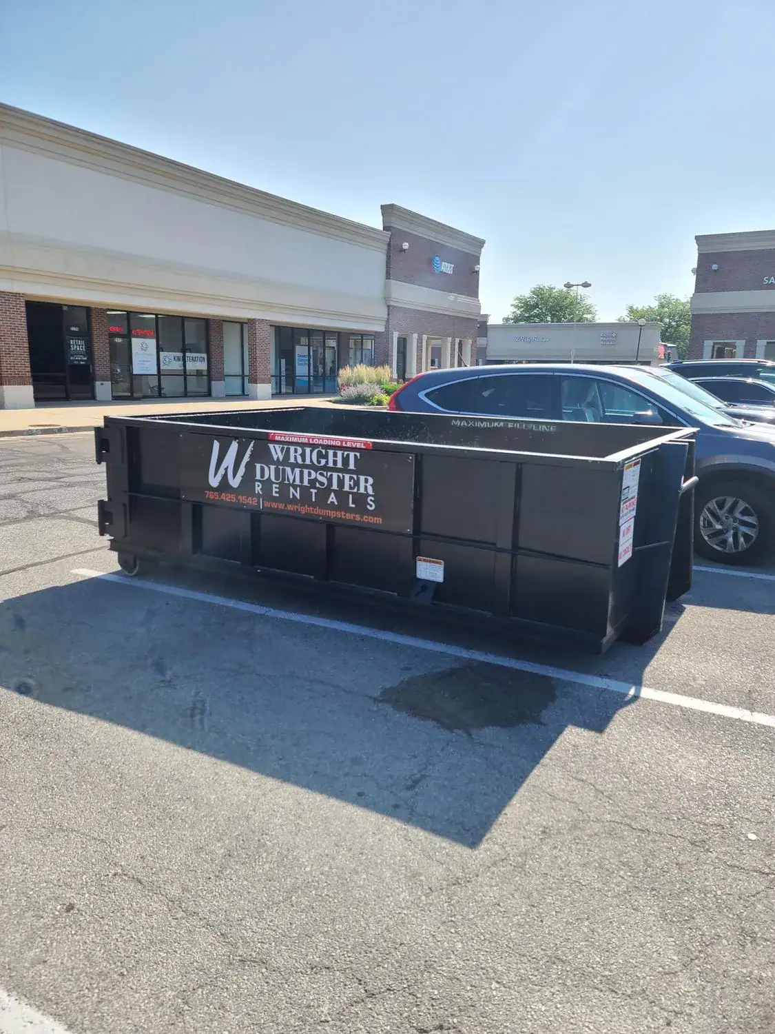 An image of black dumpster in the parking lot