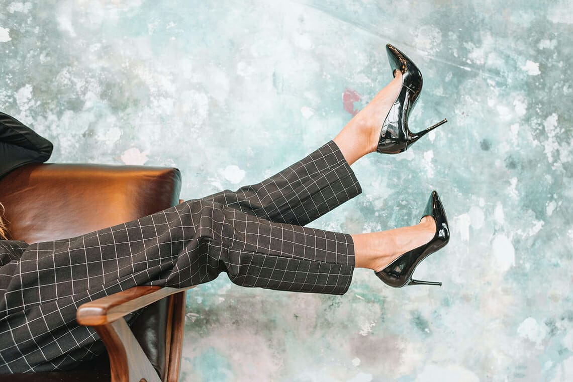A woman's legs in stylish trousers and black heels