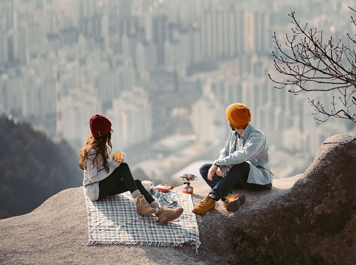 a man and a women sitting on a picnic blanket