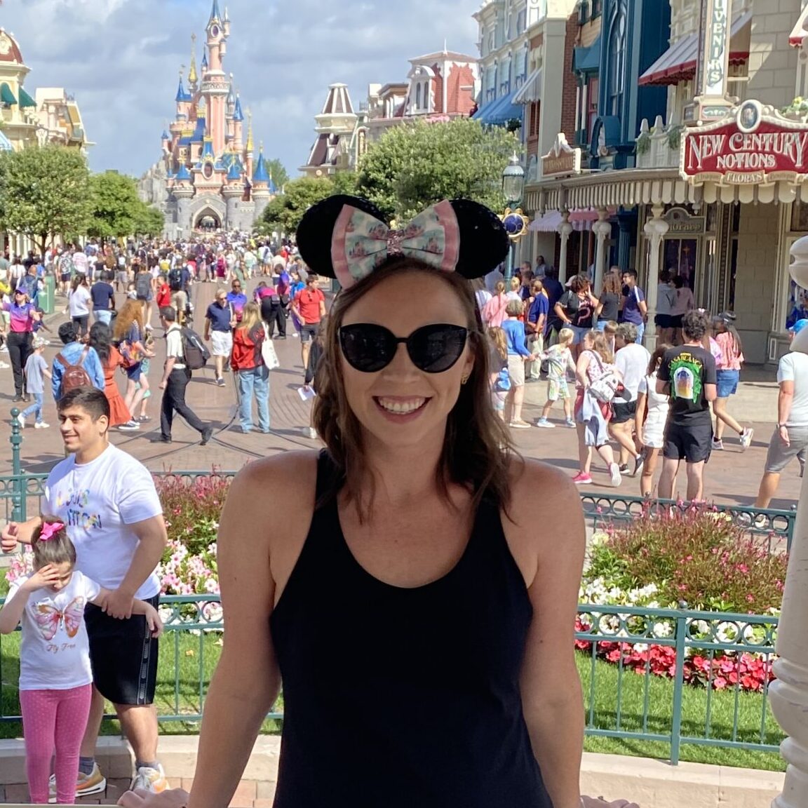 Disneyland theme park entrance with visitors and iconic castle in background.