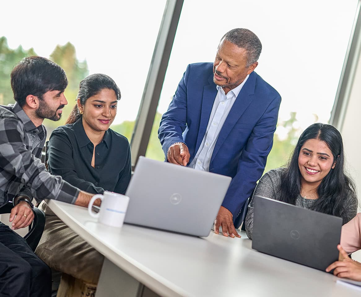 Businessman meets with his coworkers in a board room while looking at laptops