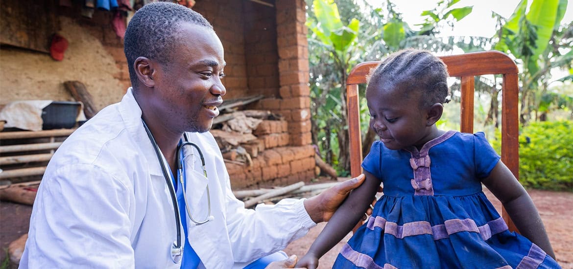 Health worker engaging with young girl in rural African setting.