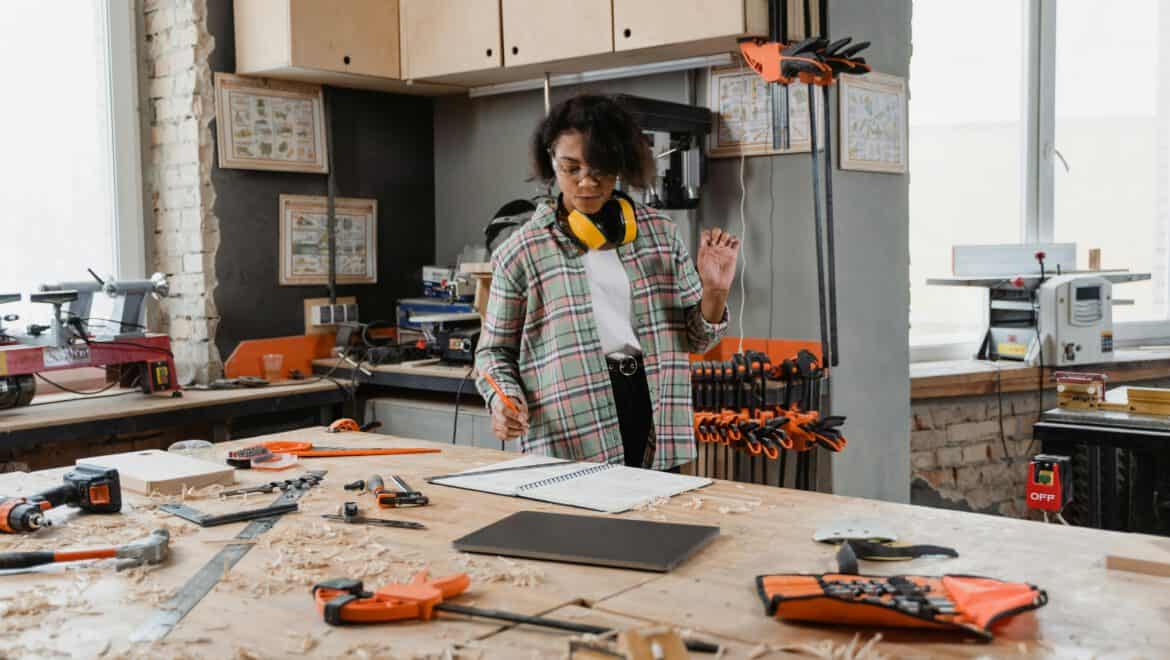 Frau in Werkstatt arbeitet an Holzprojekten mit Werkzeugen und Materialien.
