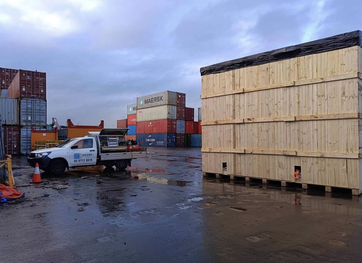 wooden shipping crate with image of shipping containers and ute in background