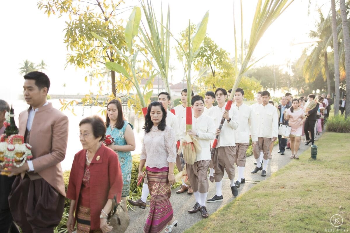 The groom and his mother lead the Khan Maak procession, with groomsmen carrying banana and sugarcane plants, at Dusit Thani Hua Hin