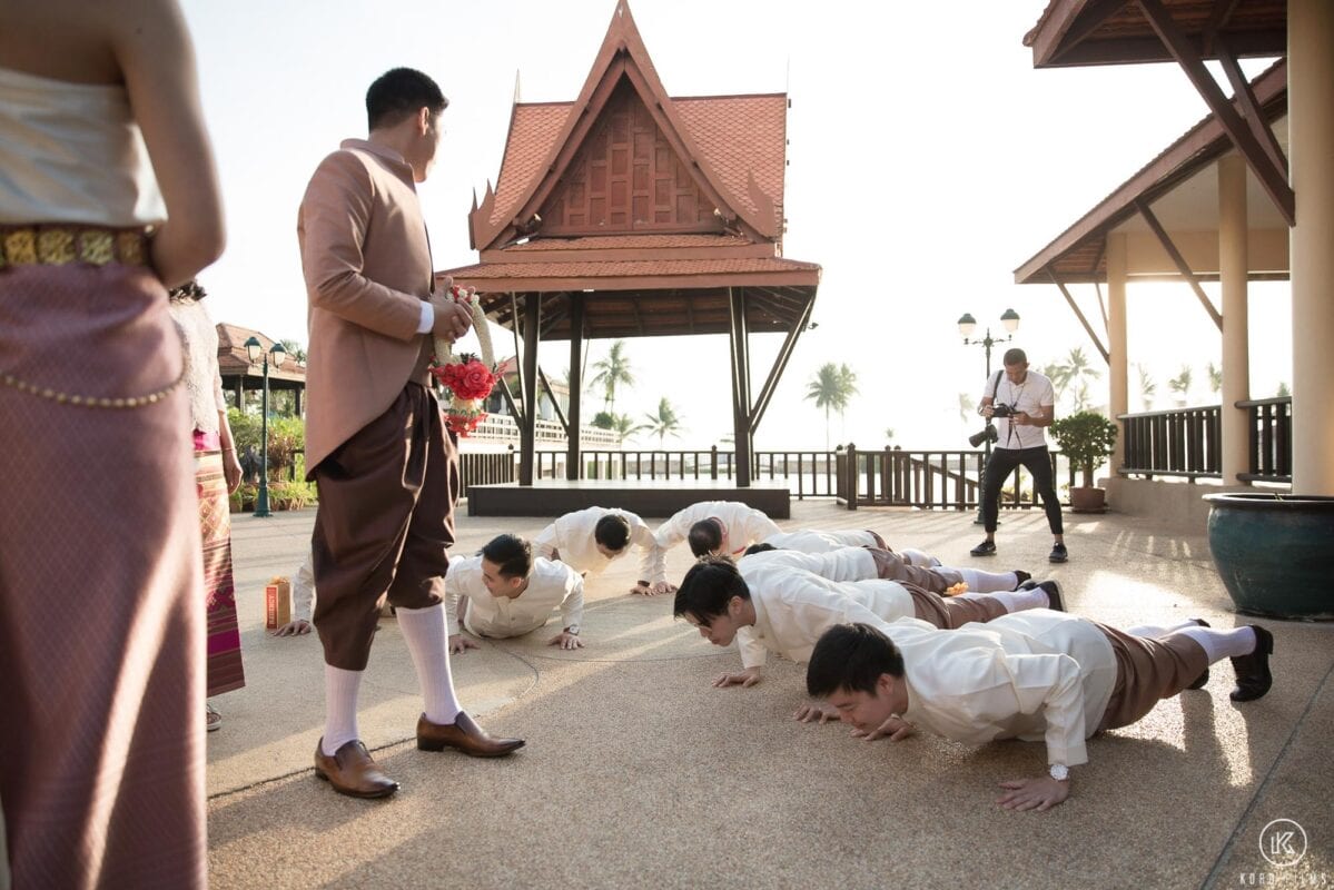 Groomsmen do push-ups at the door games while the groom waits to pass the gate at Dusit Thani Hua Hin