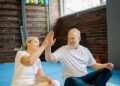 Energetic senior couple enjoying yoga, sharing a joyful high-five at the gym., tags: functional strength - pexel
