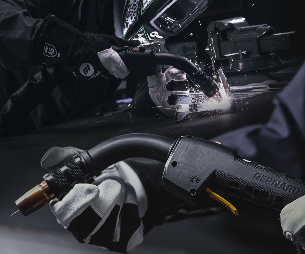 Welder using a Bernard Clean Air E welding gun for MIG welding with Bernard welding guns displayed.