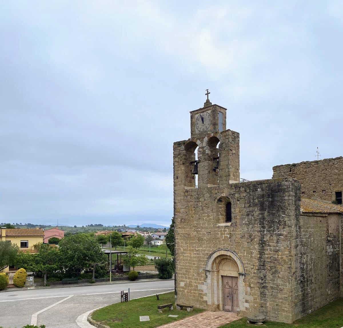 Ancient stone church with clock tower in a rural village. Historic architecture, picturesque landscape, and serene atmosphere capture the charm of Can Camades, a historic destination.