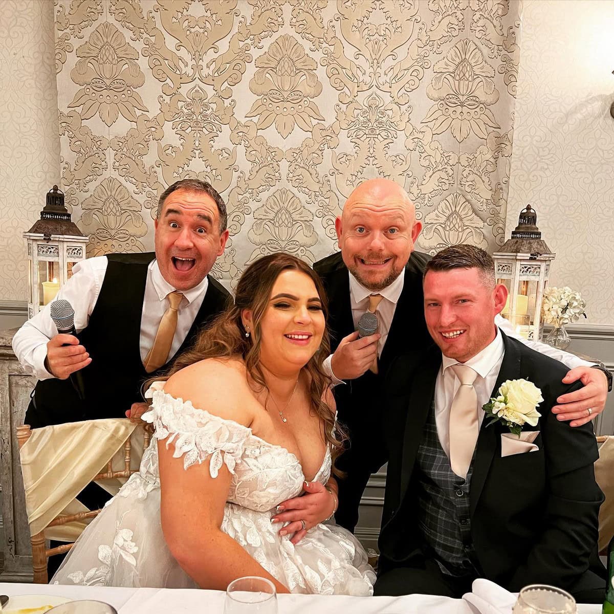 The Sing Along Waiters performing surprise entertainment at luxury UK wedding venue, award-winning singing waiters with microphones and newlyweds, featuring ornate damask wallpaper and vintage lanterns, premium Manchester wedding entertainment specialists