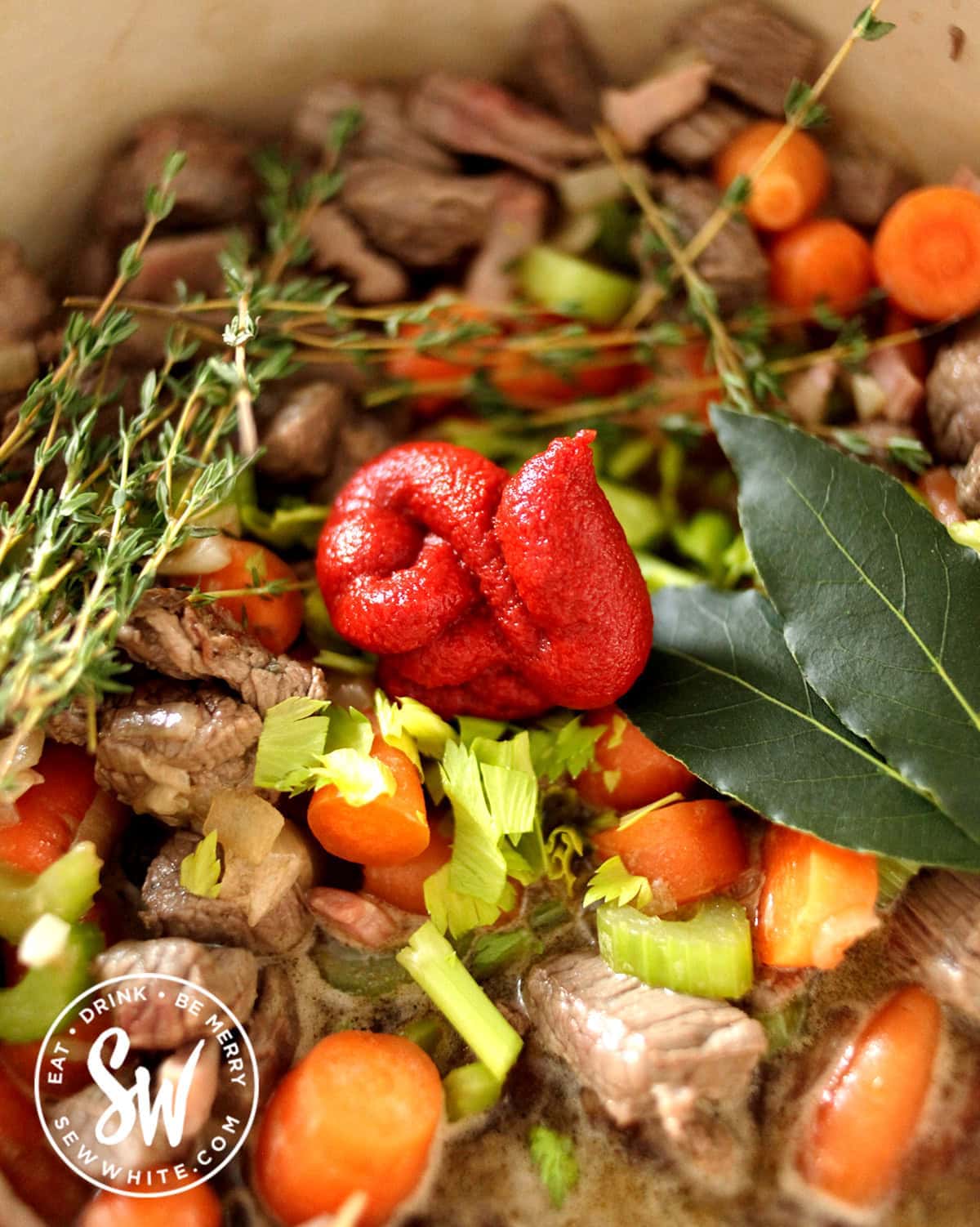 adding tomato puree and fresh herbs to the steak pie filling