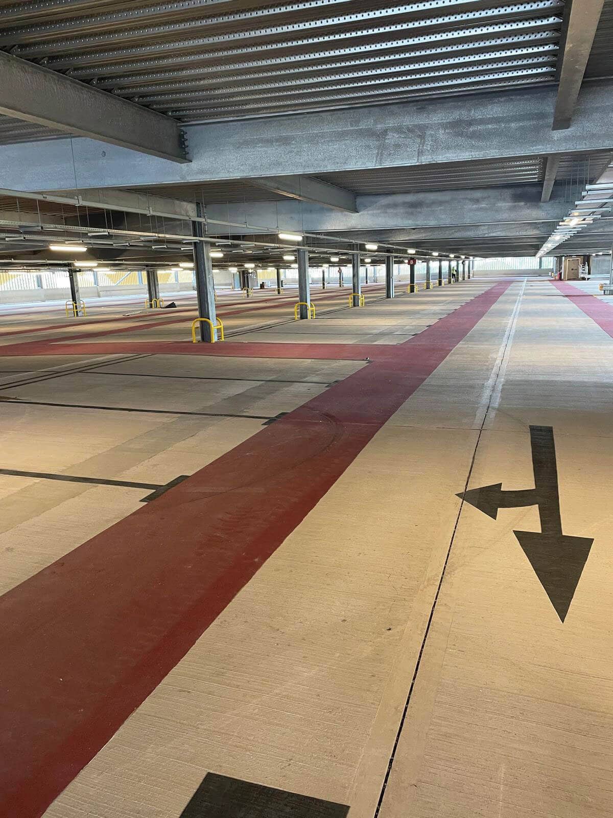Directional arrow and red traffic lane markings inside Arle Court Car Park multi-storey structure