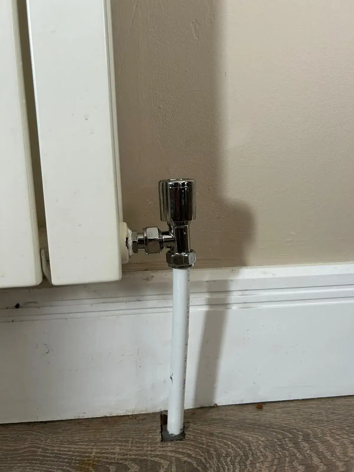 Newly installed modern chrome lockshield radiator valve connected to a white designer radiator, completed by NB Gas & Plumbing Engineer in Glasgow.