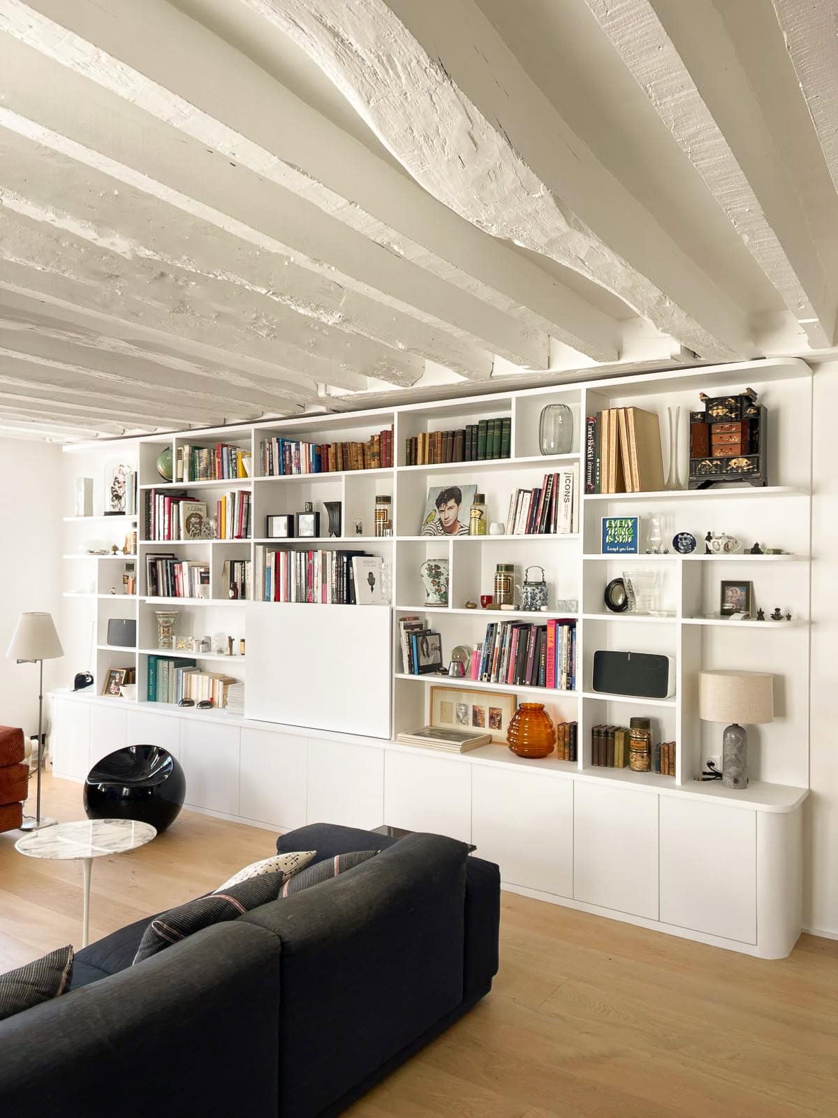 bibliotheque blanche sur mesure dans un appartement parisien avec des poiutres blanches