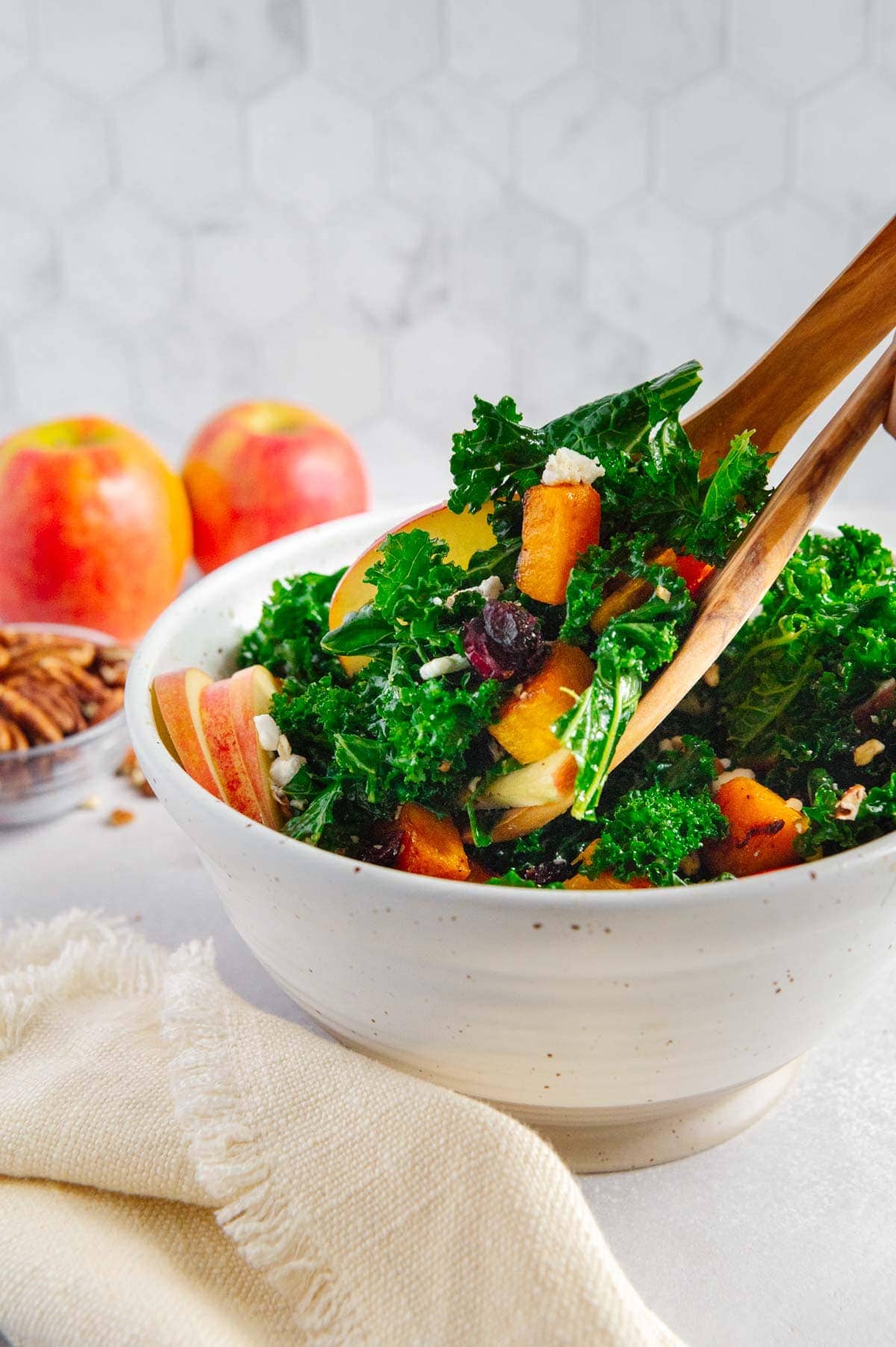 Fall harvest salad being tossed in a large serving bowl.