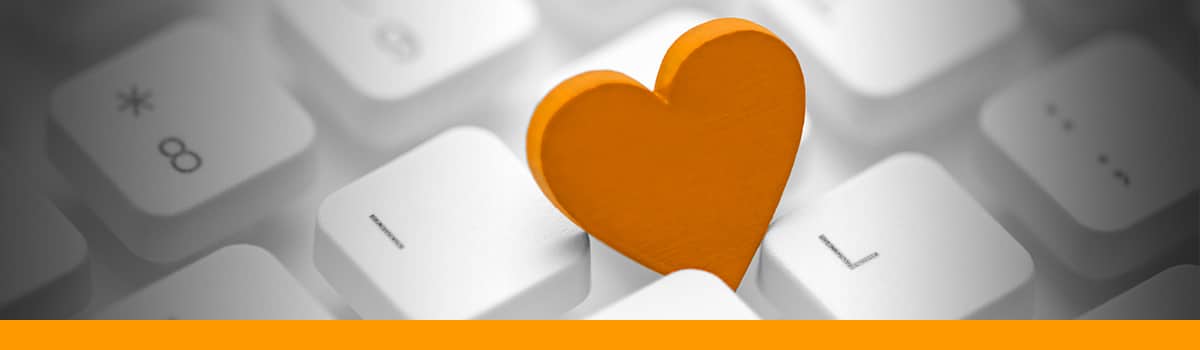 A keyboard with an orange heart laying on top