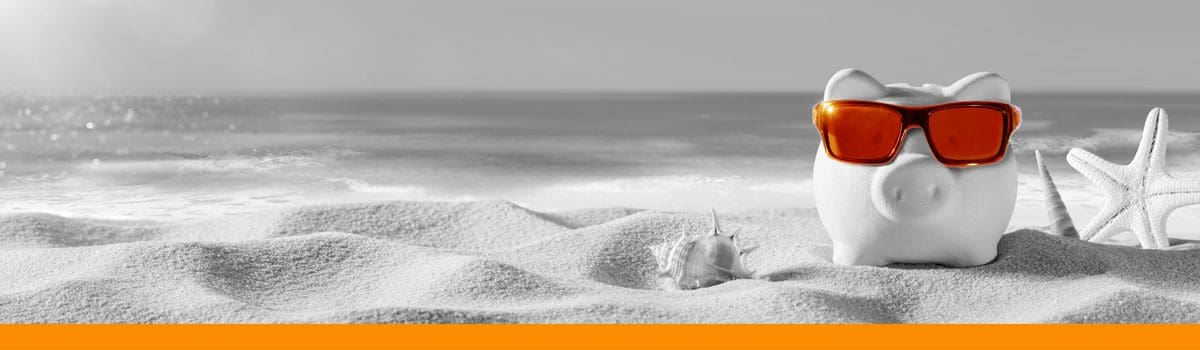 A piggybank on the beach with sunglasses on