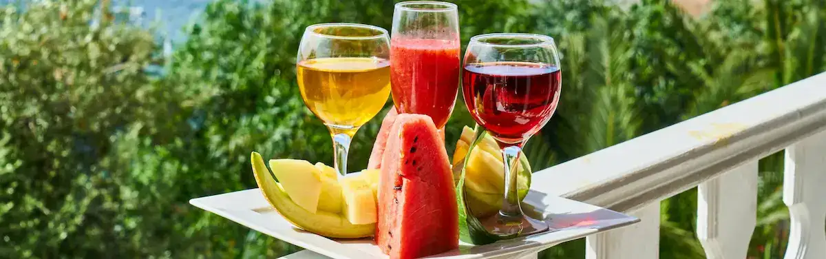 Gesundes Leben: Vitale Ernährung und Genuss Frische Wassermelonen- und Melonenstücke neben farbenfrohen Fruchtsäften und Smoothies auf einem weißen Teller; ein inspirierendes Beispiel für unsere Themenwelten: Ihr Kompass für ein gesundes Leben.