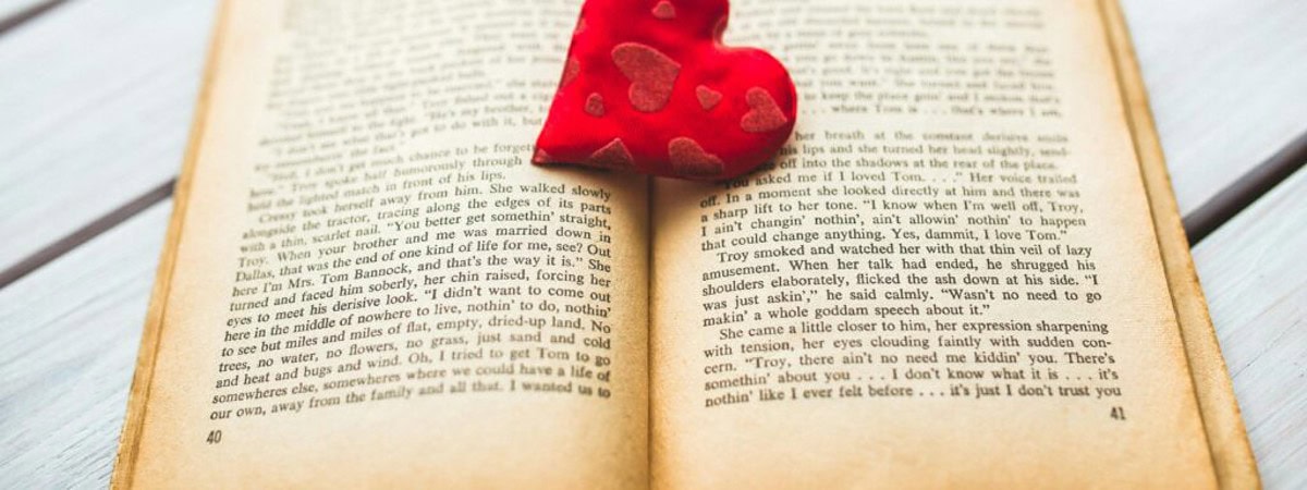 red love heart old 6369 A red heart rests in an open vintage book, evoking romance.