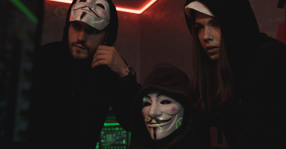 A group of people wearing Guy Fawkes masks in a dark tech-themed room, suggesting anonymity and hacking activities.