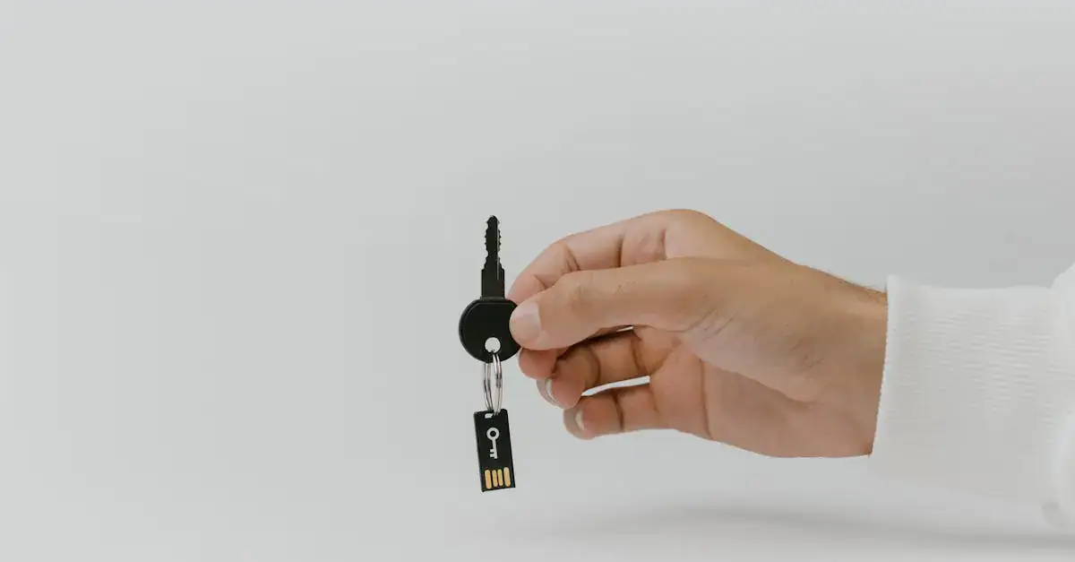 Hand holding keychain with integrated USB flash drive against a plain background.