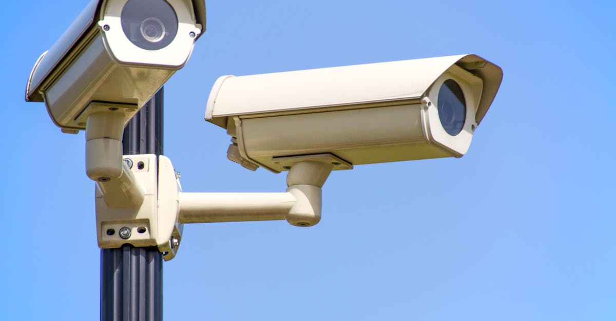 Outdoor security cameras mounted on a pole against a clear blue sky, ensuring vigilant surveillance.