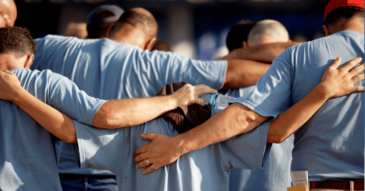 Blog Title Image of people standing with arms around each other praying.
