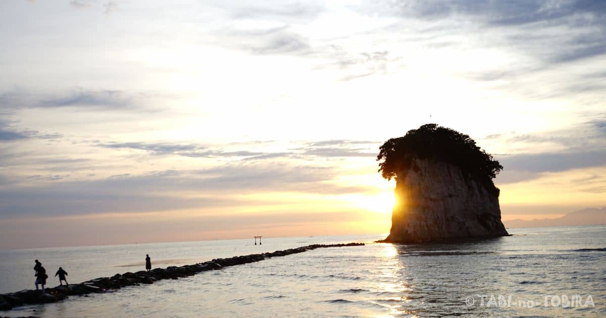 子供たちが石の道を朝日に照らされて見附島に向かって歩く様子