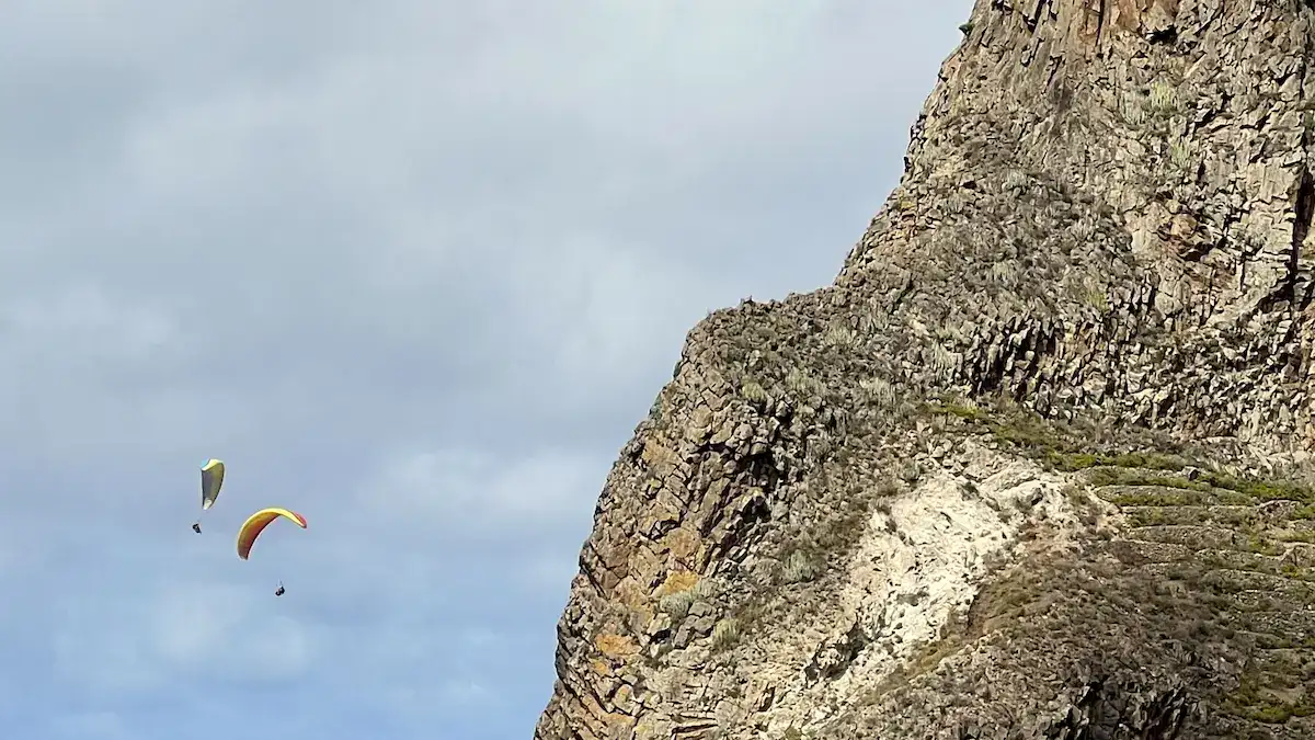 Dos parapentes volando junto a la pared rocosa de los acantilados de Anaga