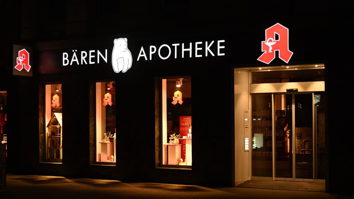 Außenansicht der Bären Apotheke bei Nacht mit beleuchteter Apothekenwerbung.