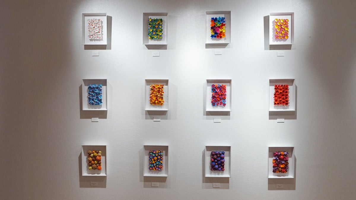 Kazumasa Mizokami Exhibition scene 2　The 12 calendars are small terracotta plates decorated with small flower-like shapes, and are decorated with brightly colored designs in 12 different designs arranged in three columns and four rows.
