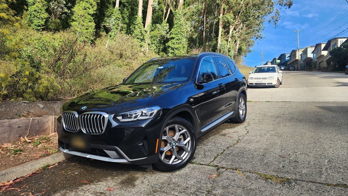 Black BMW X3 parked on a hillside street after its detail
