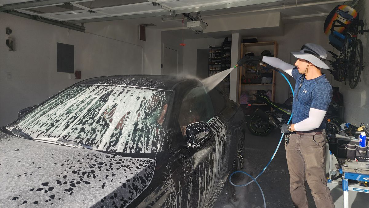 Guillermo rinsing foam off a car inside a garage
