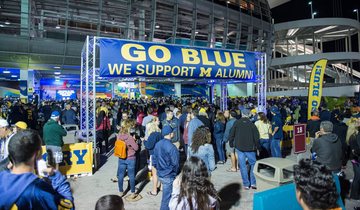 Michigan Orange Bowl tailgate with a banner that reads, "Go Blue, We Support M Alumni"
