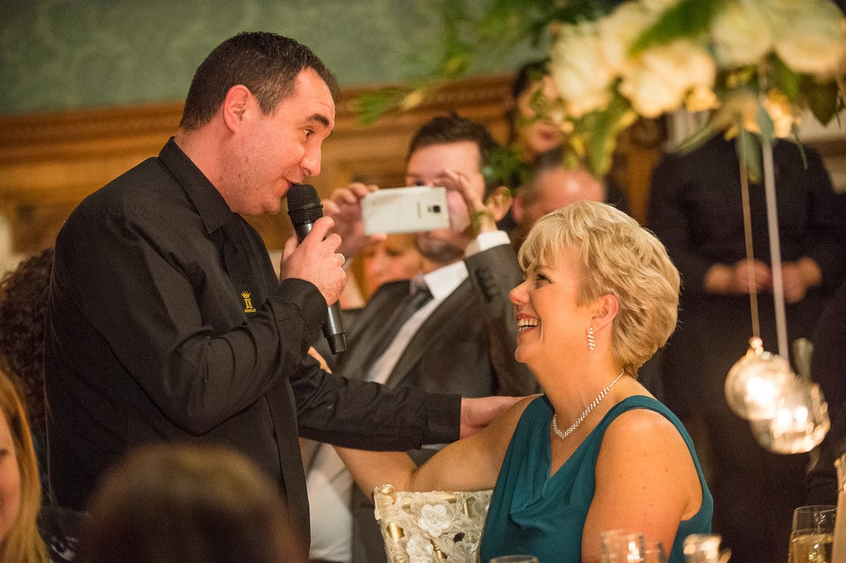Singing waiter performer serenading a delighted wedding guest during an interactive moment at Knowsley Hall, capturing genuine laughter and entertainment