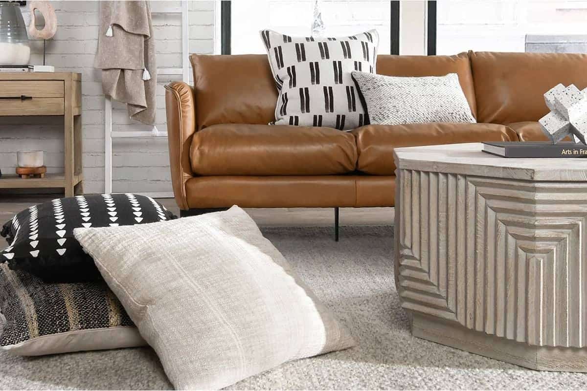 Modern living room with leather sofa, decorative pillows, and textured coffee table for cozy ambiance.