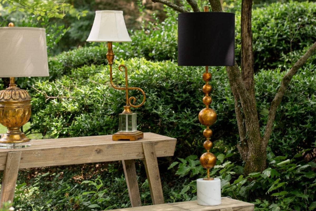 Elegant outdoor lamps with gold accents and black/white shades in garden.