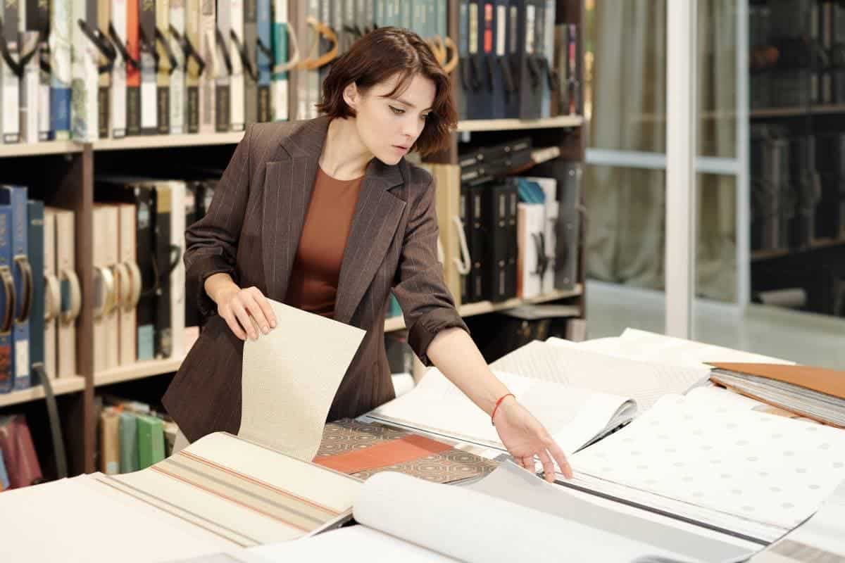 Woman reviewing fabric samples in a library-style design studio.