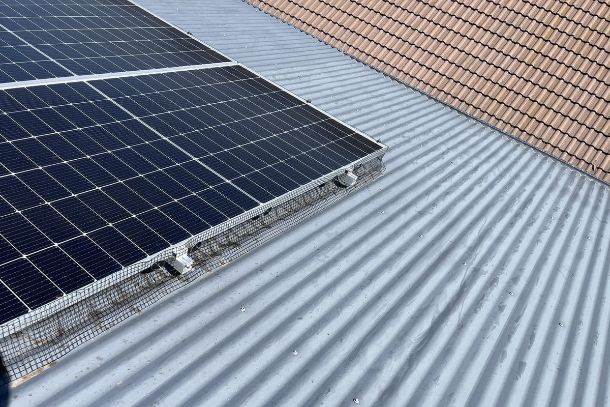 Black bird proofing mesh closing the gap along the edge of a solar array on a corrugated metal roof.