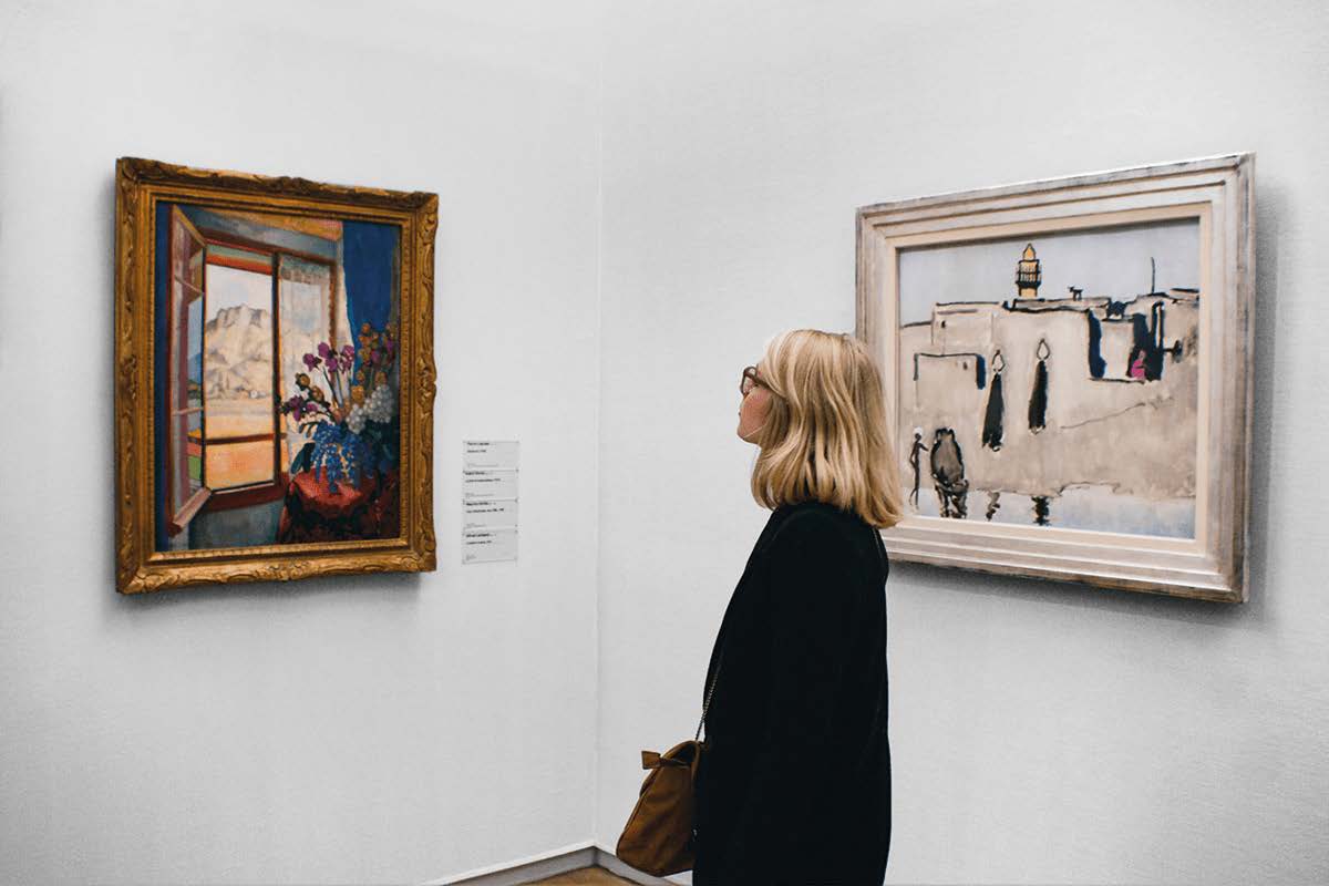 Frau betrachtet zwei Gemälde in einem Museum.